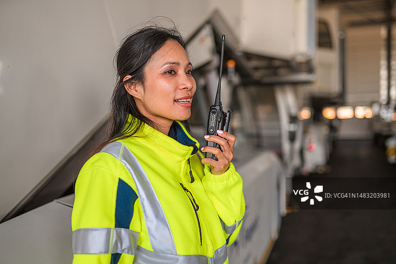 亚裔女性客梯协调员正在使用对讲机图片素材