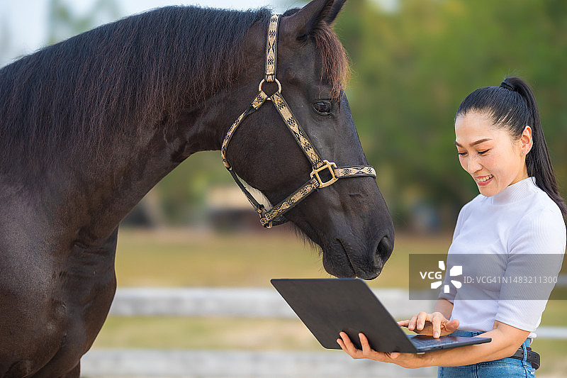 亚洲女农民在马场用电脑管理马匹健康图片素材