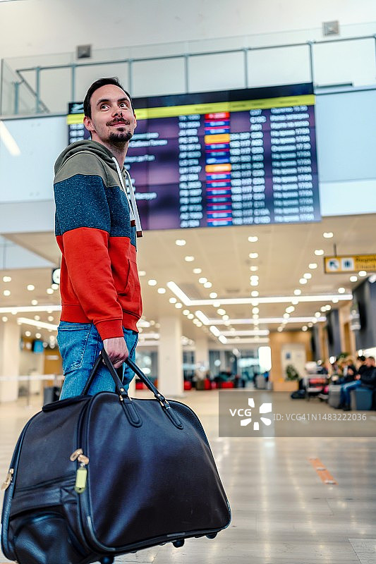 年轻男人在国际机场查看航班信息图片素材