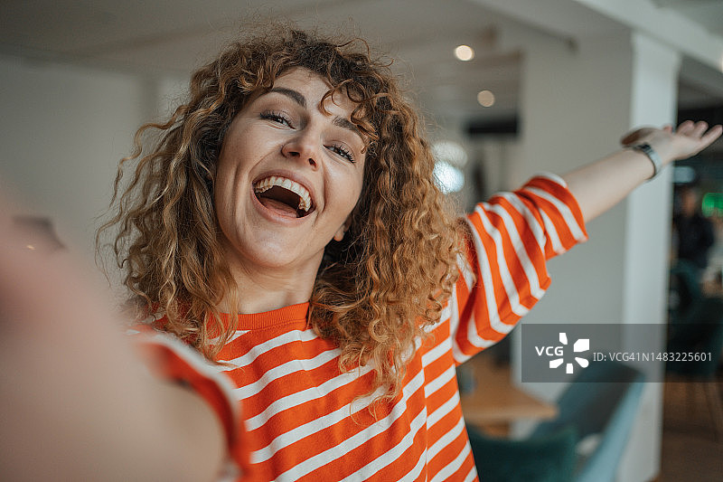 年轻卷发女孩在常去的咖啡馆自拍图片素材