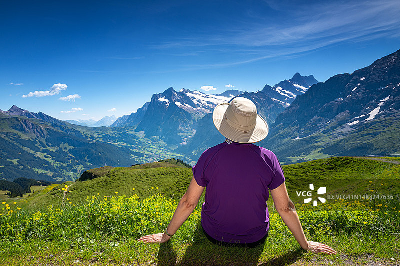 瑞士旅游：徒步者坐在曼lichen小山顶上，欣赏少女峰地区瑞士阿尔卑斯山的景色图片素材