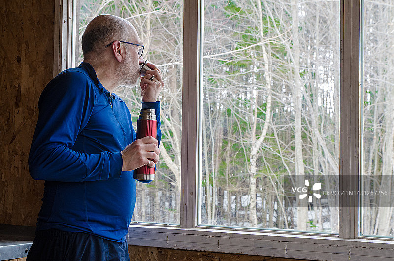 中年男人在小木屋窗边喝咖啡图片素材