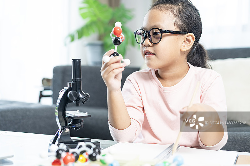 在家使用塑料原子模型进行科学教育的小学生，家庭教育概念图片素材