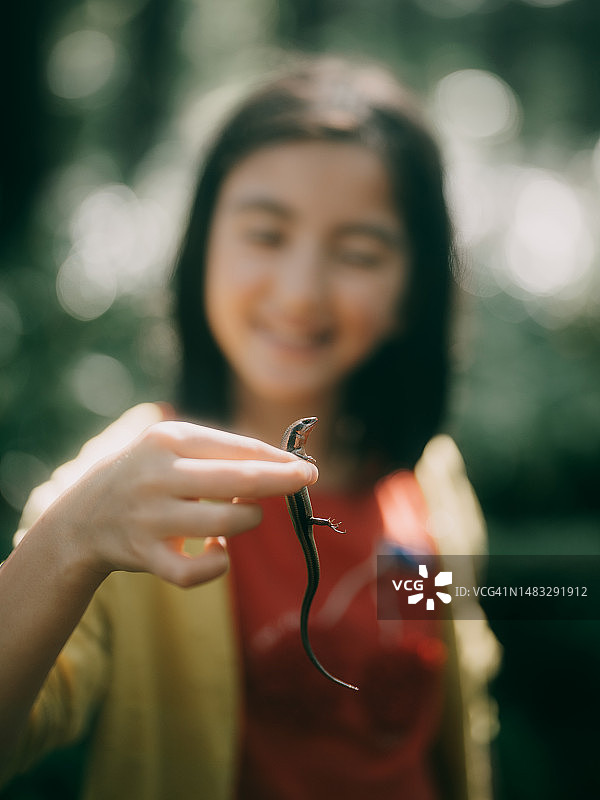 在森林里手拿蜥蜴的年轻女孩图片素材