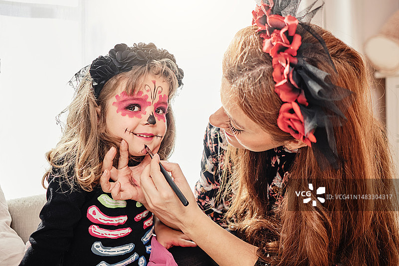 女人为女儿化妆，制作万圣节服装图片素材