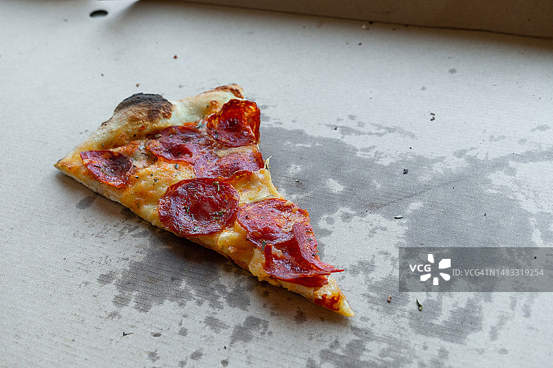 比萨店餐桌上的美味意大利比萨，配有比萨盒和外卖盒，切片比萨配有番茄、意大利辣香肠和奶酪，不健康的生活方式、暴饮暴食、垃圾食品、快餐概念，送货上门或工作场所图片素材