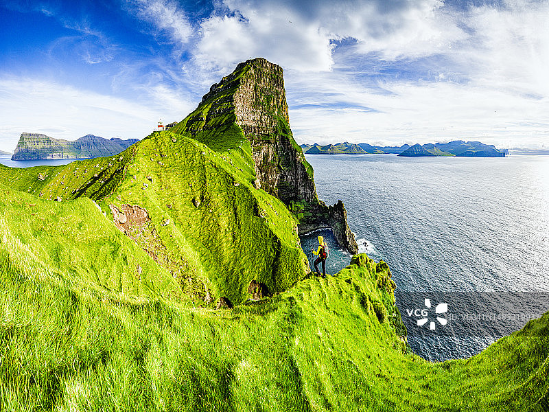 徒步者欣赏着悬崖上的灯塔图片素材