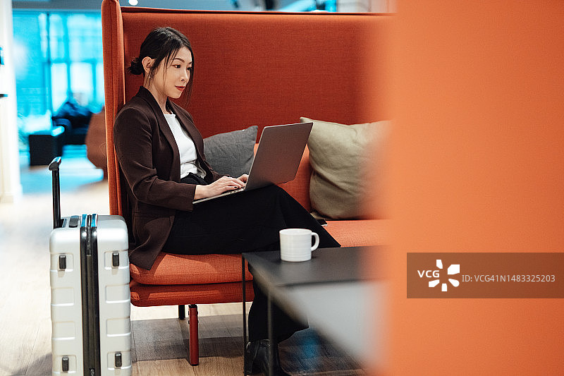 在机场贵宾休息室用笔记本电脑工作的年轻亚洲女商人图片素材