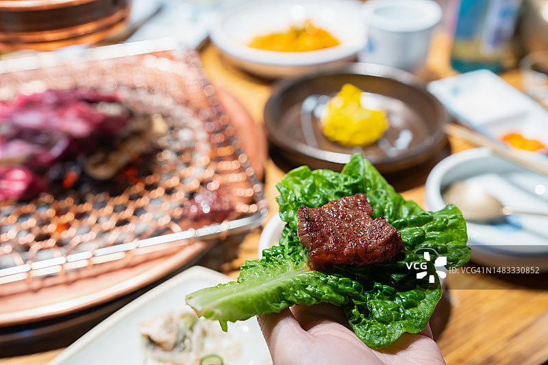 在餐厅里像韩国人一样用餐，手拿蔬菜和烤牛肉图片素材