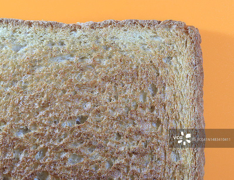 橙色背景下的蜂蜜小麦烤面包片图片素材