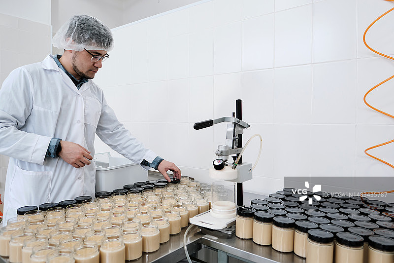 工厂工人将成品倒入玻璃容器中图片素材