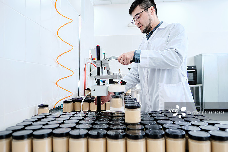 工厂工人用吸尘器清洁玻璃罐中的成品图片素材