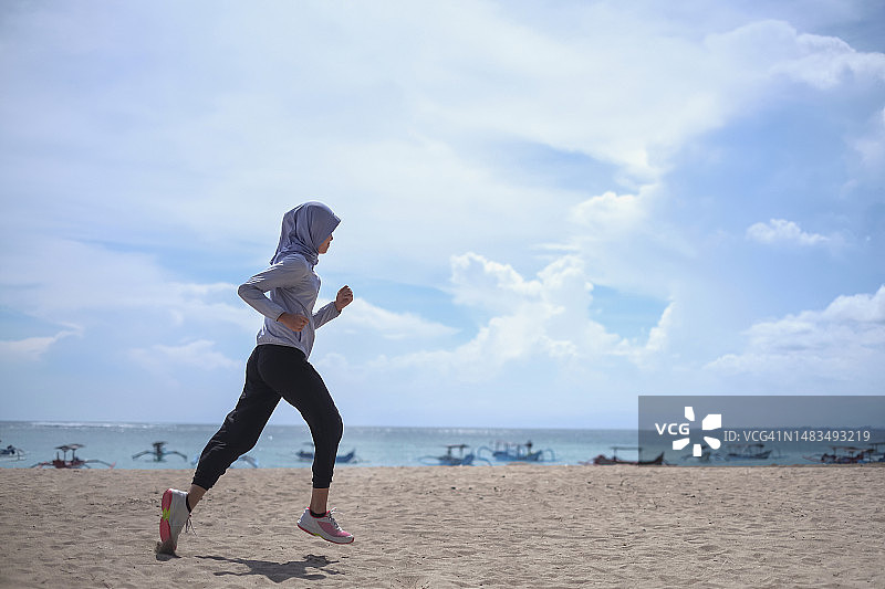 在海滩上奔跑的印度尼西亚穆斯林妇女图片素材