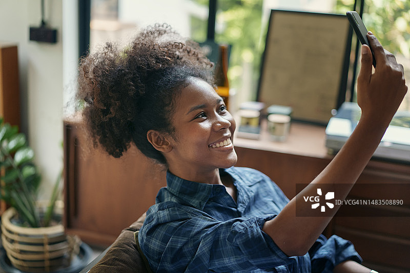 充满正能量，年轻的美国混血自由职业者在咖啡馆与朋友进行手机视频通话，数字游民概念图片素材