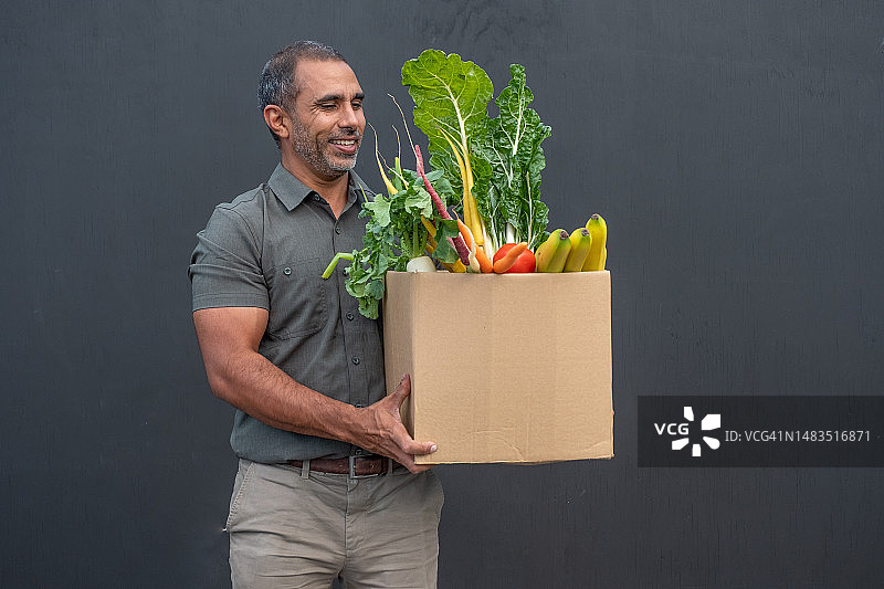 送货员搬运一箱水果和蔬菜图片素材