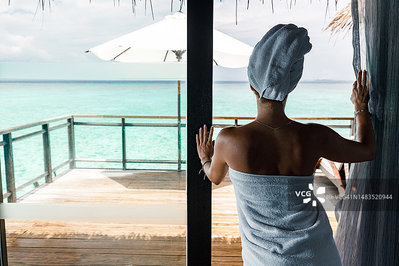 淋浴后裹着毛巾的女人在浴室里的背影图片素材
