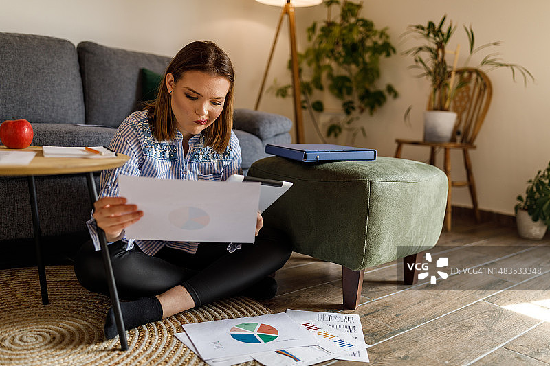 坐在客厅地板上学习营养学的年轻女学生图片素材