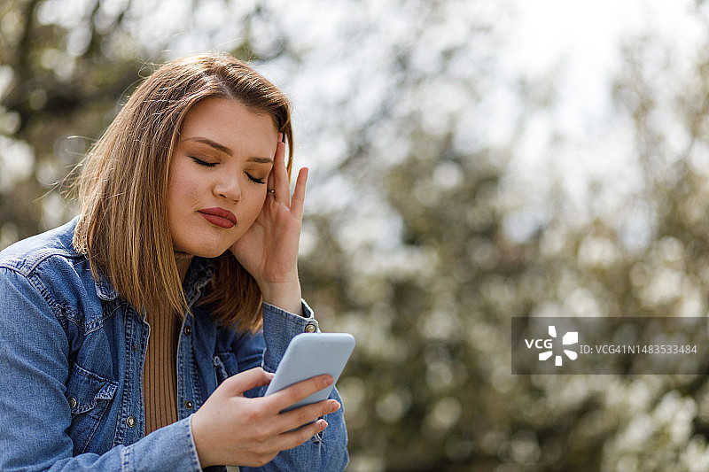 沮丧的年轻女子回复智能手机上的短信图片素材