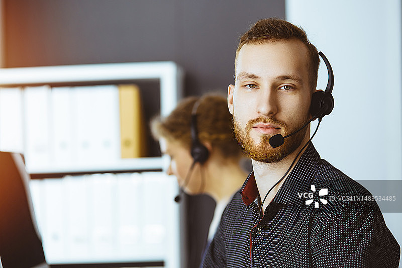 留着红胡子的商人在办公室戴耳机交谈图片素材