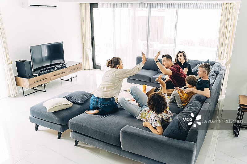 一群朋友坐在明亮客厅的沙发上聊天图片素材