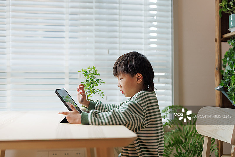 一名亚洲男孩在家使用数位平板电脑学习图片素材