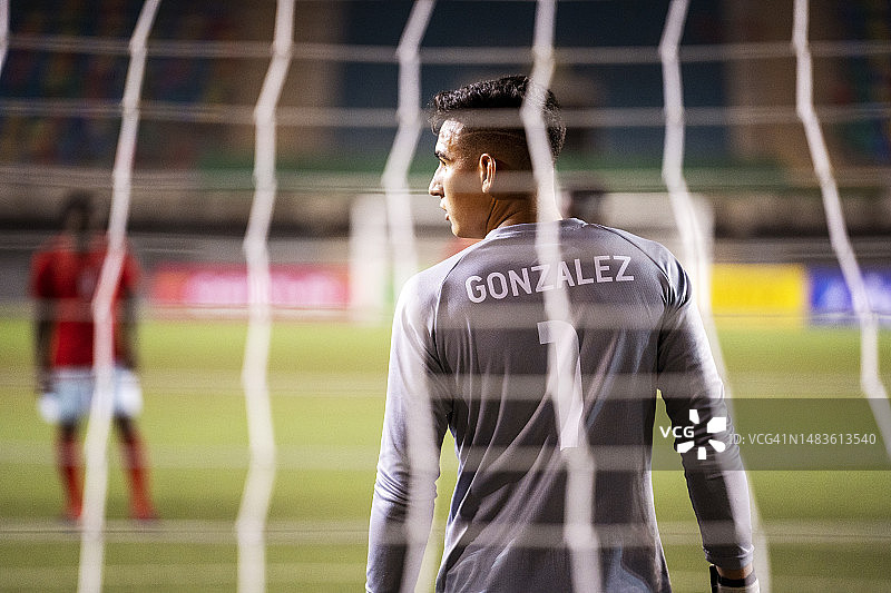 足球守门员自信地站在球网前，看向一侧图片素材