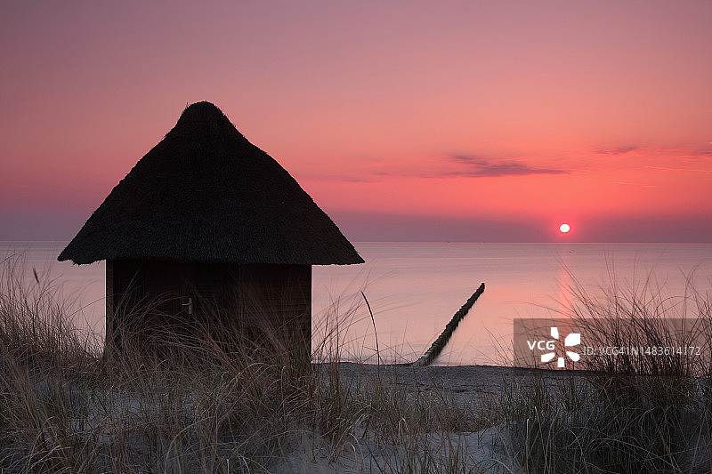 多彩日落时分海滩上的小屋图片素材