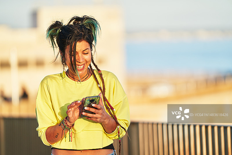快乐的女人在日落时于户外使用手机图片素材