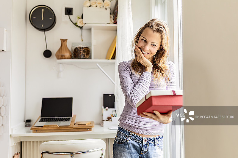 在家中窗边手拿礼品盒的女孩图片素材