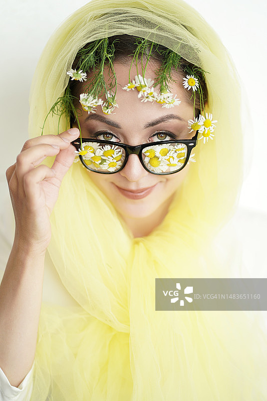 戴着雏菊花眼镜和黄色围巾的女子的夏日写真，草药医学和眼科检查概念图片素材