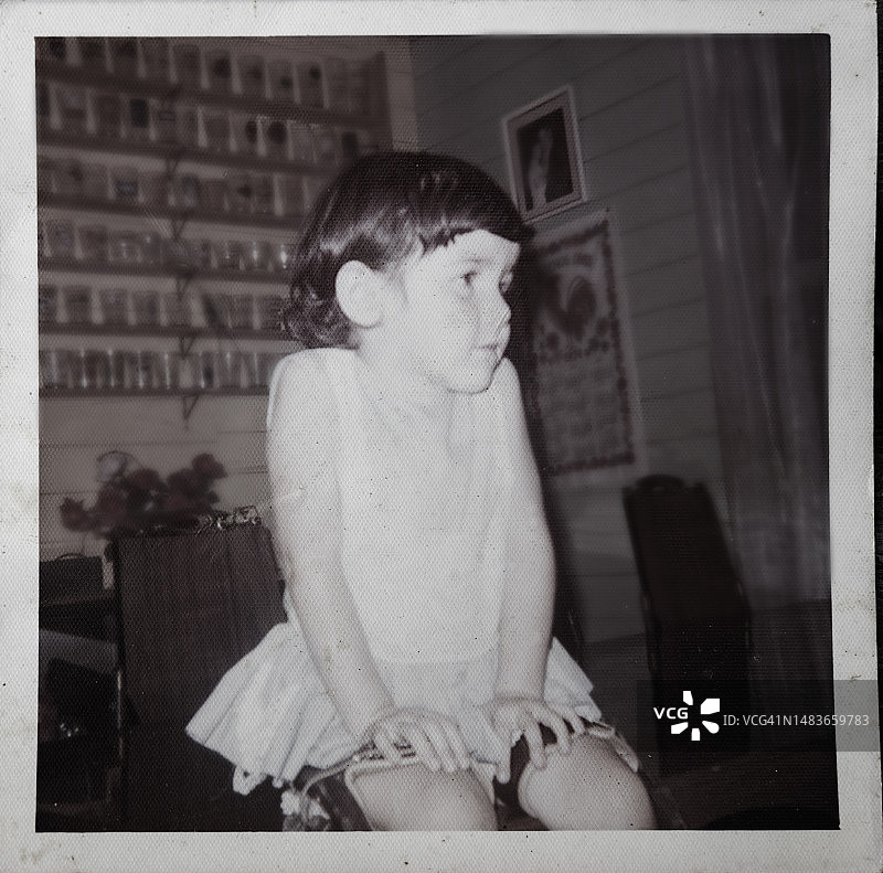 使用腿部支架坐在客厅的儿童复古肖像图片素材