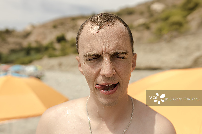 男人在阳光明媚的海滩上吐舌头图片素材