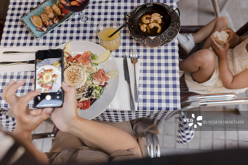 女人在餐厅用智能手机拍摄食物图片素材
