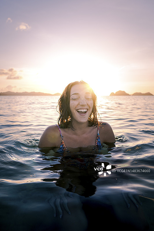 日落时分在海中游泳的快乐女人图片素材