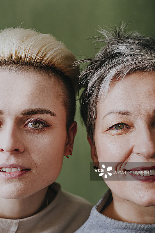 在绿色墙壁前与母亲合影的年轻女人图片素材