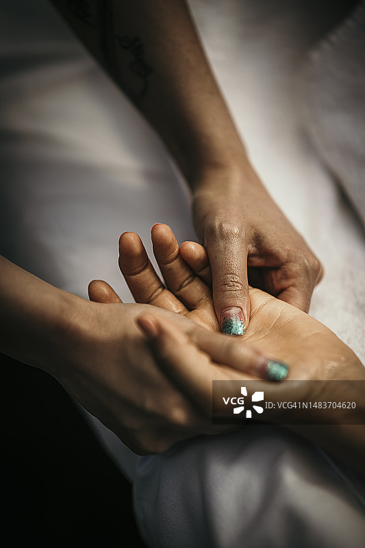 按摩治疗师按摩女性的手图片素材