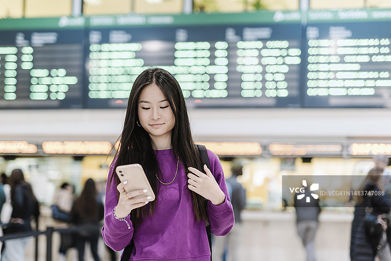年轻女子在火车站或机场看手机图片素材