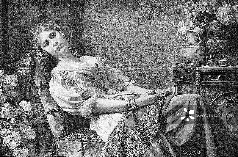 1880年德国：周日下午，年轻女子坐在客厅的扶手椅上休息，暂停缝纫或刺绣图片素材