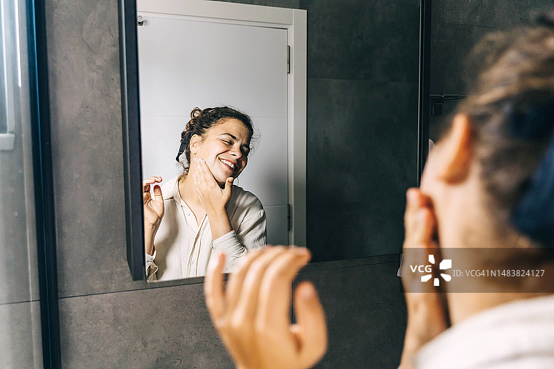 在漂亮的浴室里照镜洗脸的年轻女子图片素材