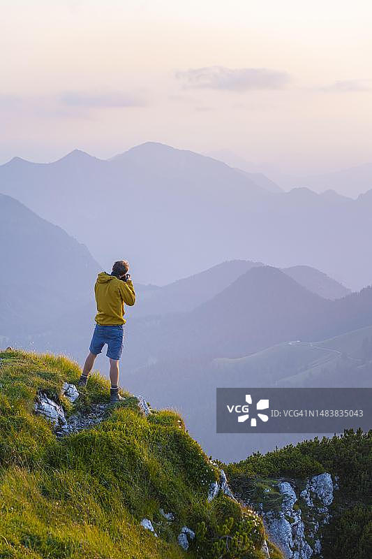 摄影师在贝内迪克滕万德峰顶日落时拍摄，背景是巴伐利亚阿尔卑斯山图片素材