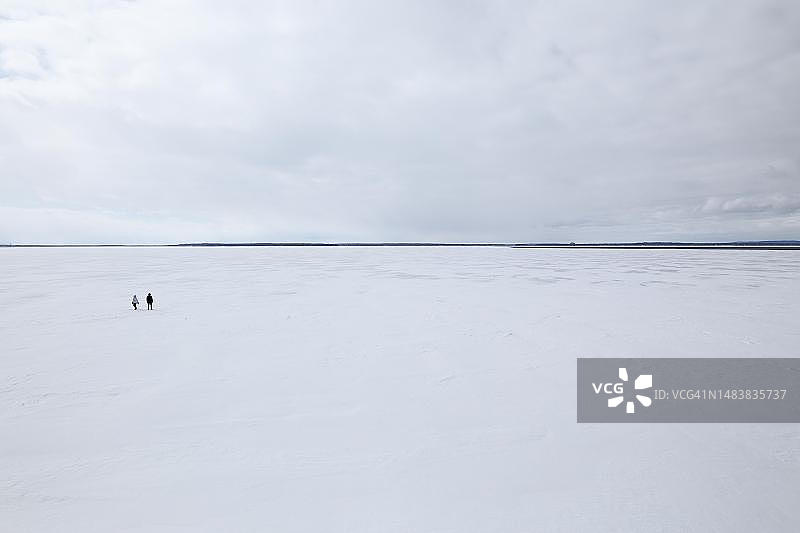 两个人站在宽阔而冰冻的河景上，圣劳伦斯河，加拿大魁北克省图片素材