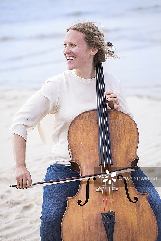 在海滩上演奏大提琴的女人图片素材