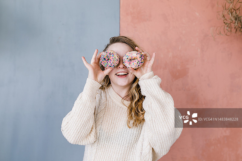 对着洒满糖霜的甜甜圈张开嘴的快乐女人图片素材