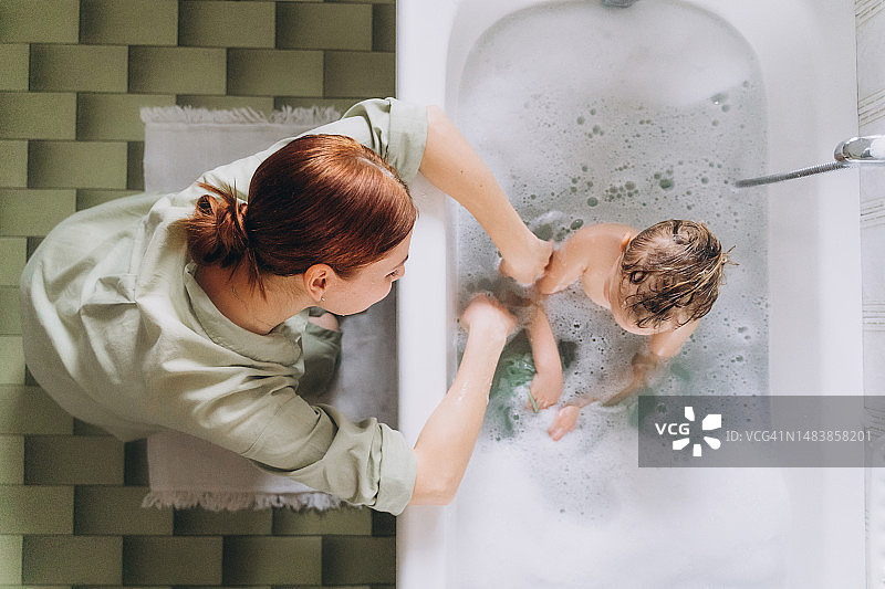 女人在浴室里给快乐的小女孩洗泡泡浴图片素材