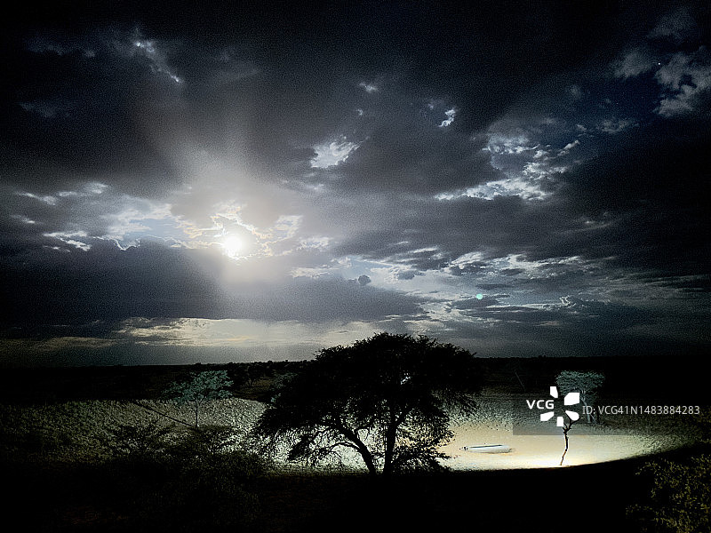 沙漠景观：满月穿过云层，水坑泛光图片素材