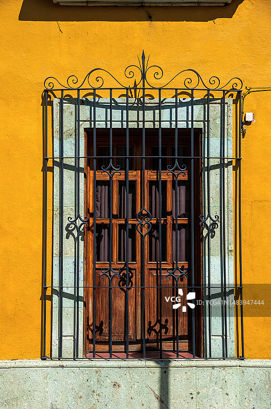 西班牙殖民风格房屋双门/窗上的华丽金属安全格栅，漆成鲜艳的黄色图片素材
