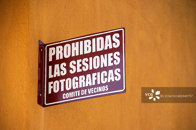 西班牙语标志，上面写着“Prohibidas las sesiones fotograficas”。墨西哥瓦哈卡州华雷斯市一条风景如画的殖民时代街道上的维奇诺斯委员会图片素材