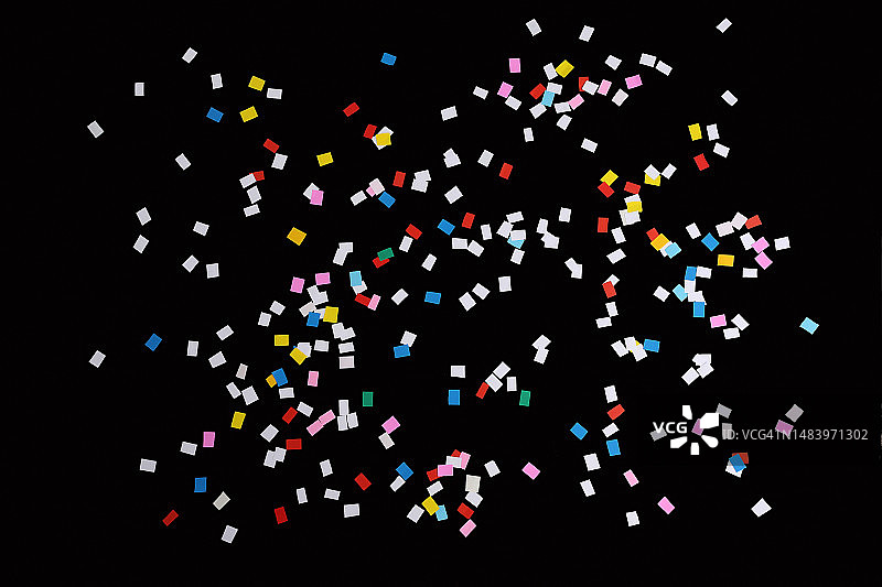 五彩纸屑、花粉、纸片，彩色纸带散落在黑色背景上，俯视角度，无人图片素材
