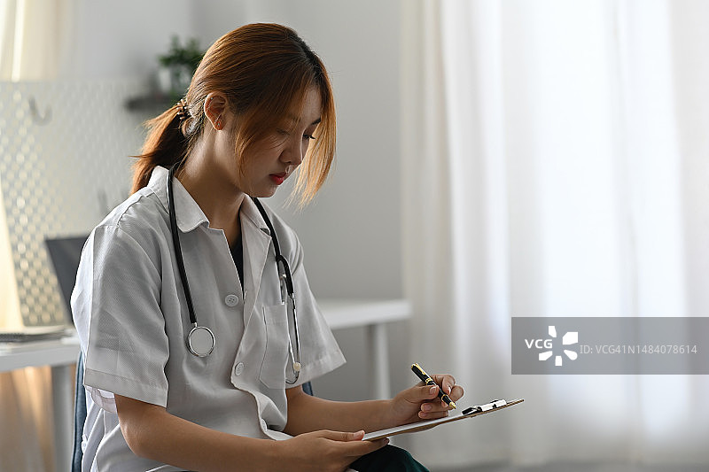 亚洲女医生在咨询病人时填写申请表，医药概念图片素材