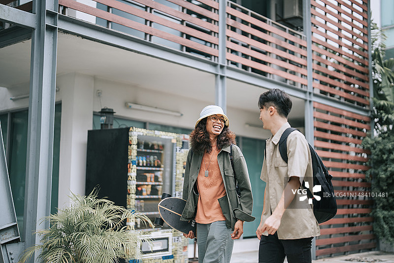 两名亚洲男大学生在校园户外边走边聊图片素材